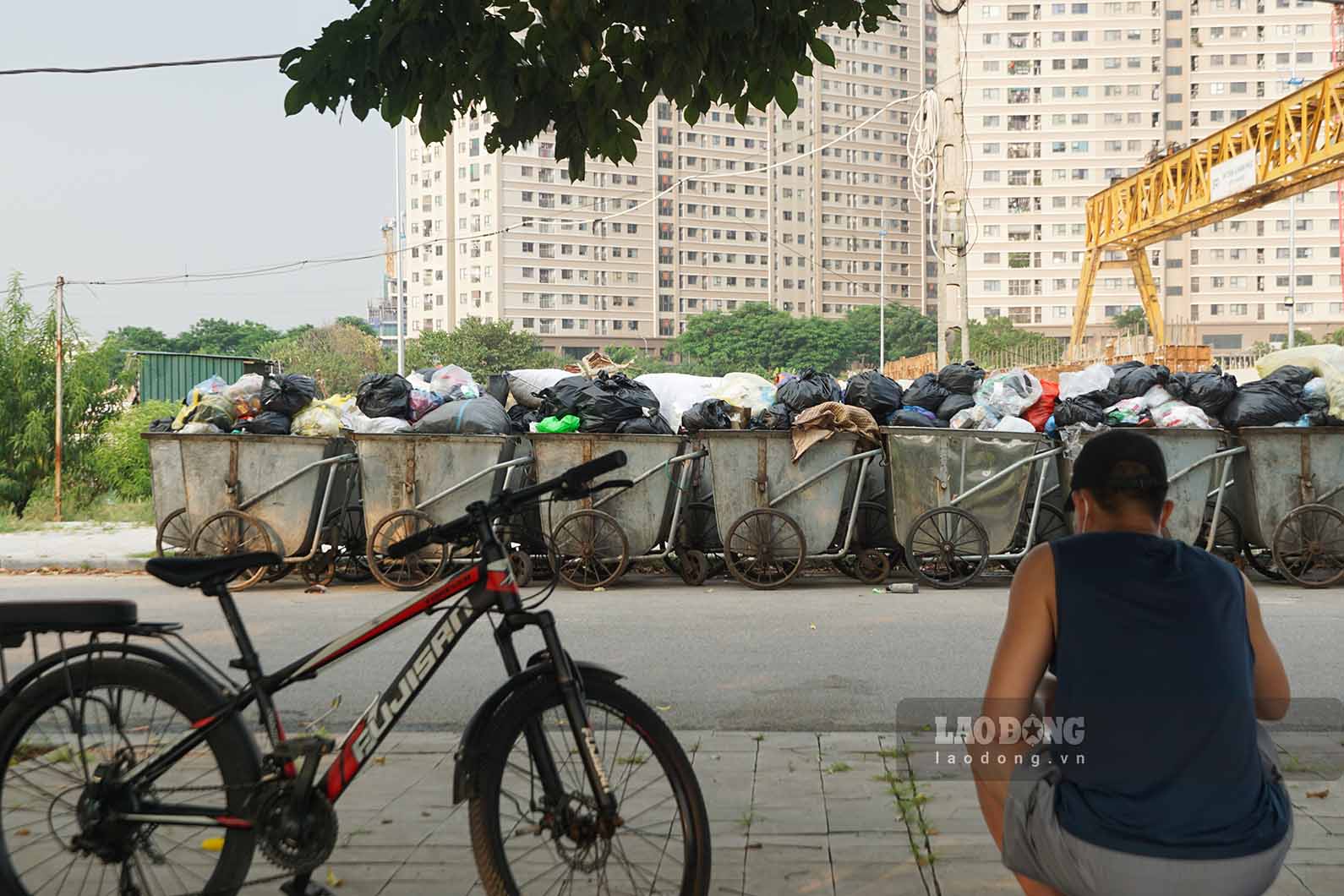 Người dân đi tập thể dục ngồi nghỉ ngay trước điểm tập kết rác thải. Ảnh chụp chiều 8.9: Hữu Vũ