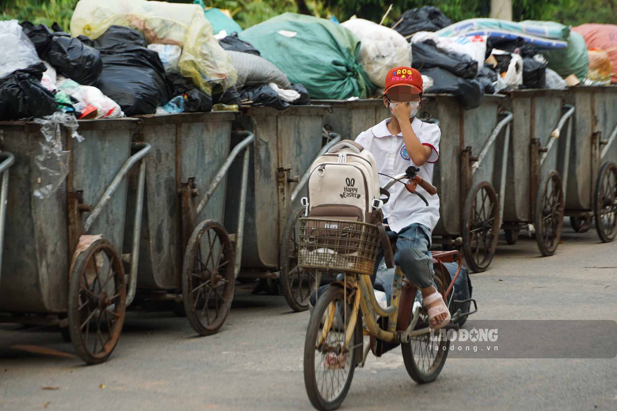 Học sinh bịt mũi đi qua điểm tập kết rác thải gần khu vực gần trường Tiểu học Yên Nghĩa. Ảnh chụp chiều 8.9: Hữu Vũ