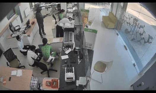 Tên cướp mặt áo đen dùng súng uy hiếp các nhân viên ngân hàng (ảnh cắt từ camera an ninh)