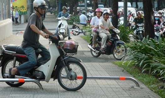 Người Sài Gòn lạng lách xe máy trên vỉa hè có barie chắn ngang. (Ảnh minh họa theo VOV.vn)