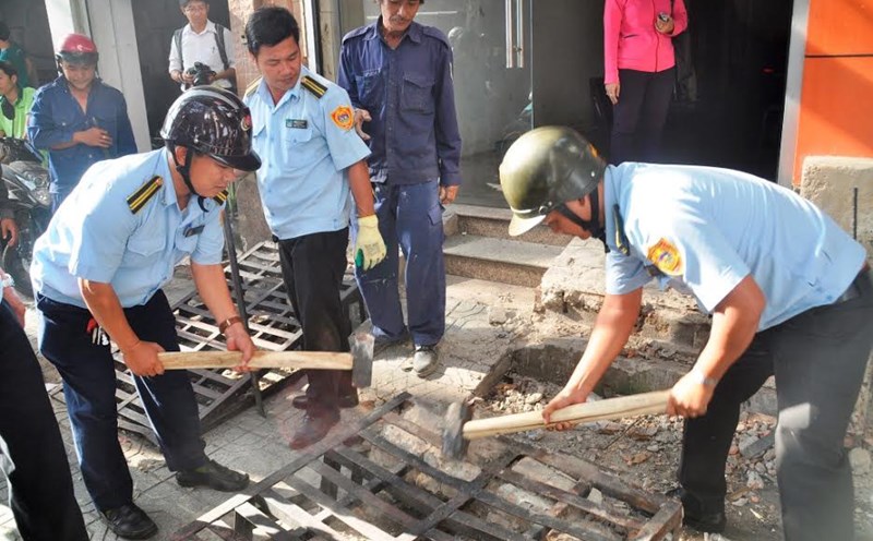 Lực lượng chức năng tháo gỡ vật cản giành lại vỉa hè cho người đi bộ (Ảnh minh họa theo Báo Mới)