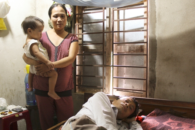 Bà Xuân bên ông Tý nằm thoi thóp trên giường bệnh vì không có tiền chữa trị. Ảnh: Hữu Long