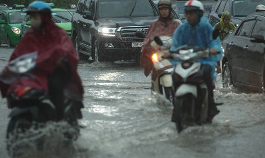 Người dân Hà Nội vất vả trên đường đến công sở trong cơn mưa dông sáng 13.6. Ảnh: Theo 24h.com