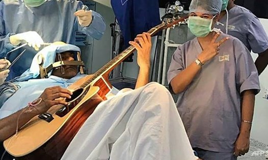 Nhạc sĩ Ấn Độ Abhishek Prasad chơi guitar trong khi các bác sĩ tiến hành phẫu thuật. Ảnh: AFP