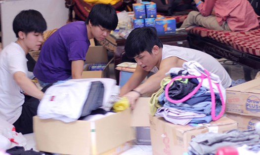Tình nguyện viên nhà tạm lánh phân loại quần áo được quyên góp