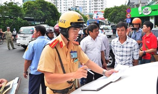 Ông Đoàn Ngọc Hải (áo trắng) yêu cầu CSGT xử nghiêm những xe đậu trái phép, bất hợp tác trước cao ốc trên đường Nguyễn Trãi, quận 1.