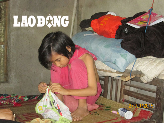 Bé Diệu Ly, 9 tuổi, vá áo cho em và cho mình.