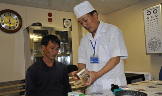 Bác sĩ Thái Đàm Lương (tàu 561) phát thuốc cho ngư dân Quảng Ngãi vào khám bệnh. Ảnh: NGỌC NAM