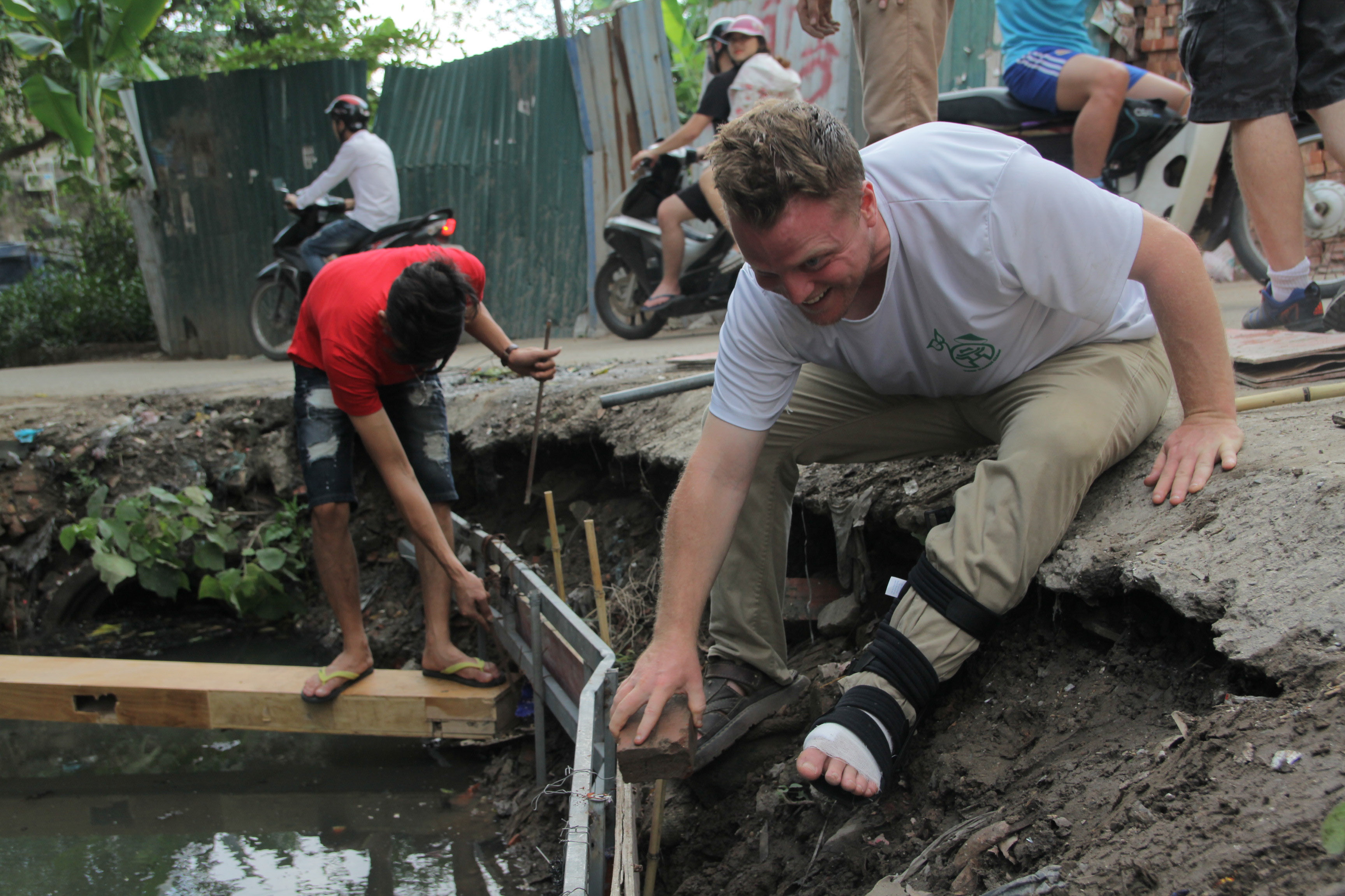 “Ông Tây dọn rác” đóng cọc làm rào chắn chuẩn bị biến mương nước thành một khu vườn nhiều cây xanh. Ảnh: PV