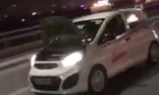 Chiếc taxi bị lật nắp capo nhưng tài xế vẫn ngang nhiên đánh võng phóng nhanh trên cầu Nhật Tân. Ảnh cắt từ video.