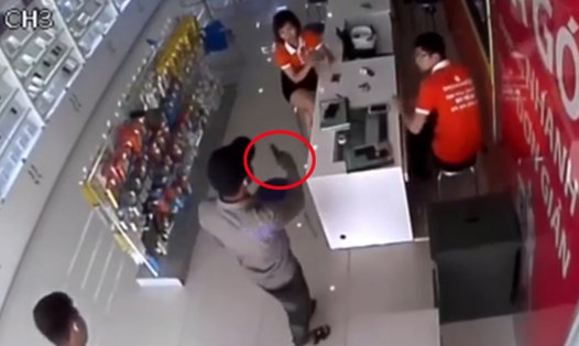 Một thanh niên mang súng (trong vòng đỏ) đe dọa nhân viên. Ảnh cắt từ clip.