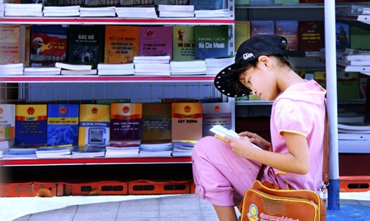 Em bé say sưa đọc sách "ké" trong Hội chợ sách ở Tp Cần Thơ (tháng 3/2015). Ảnh: Triệu Vinh