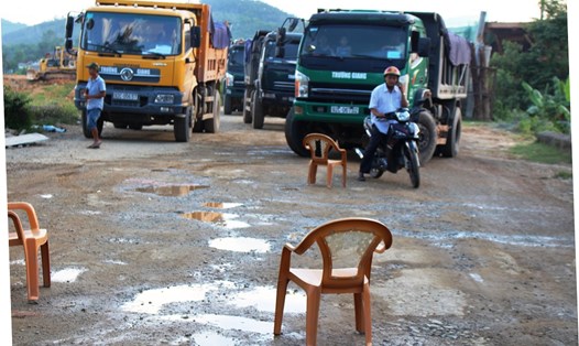 Người dân mang ghế ra chặn đường nhằm ngăn các đoàn xe tải chở đất gây bụi bặm. Ảnh: LP