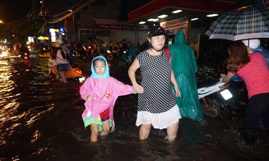 Người lớn và trẻ nhỏ bì bõm lội nước ngập về nhà trên đường Nguyễn Xí, Q.Bình Thạnh. Ảnh: M.Q