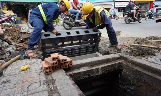 Nhân viên Công ty Thoát nước đô thị TPHCM lắp miệng hố ga kiểu mới trên đường Lê Văn Thọ (Q.Gò Vấp). Ảnh: M.Q